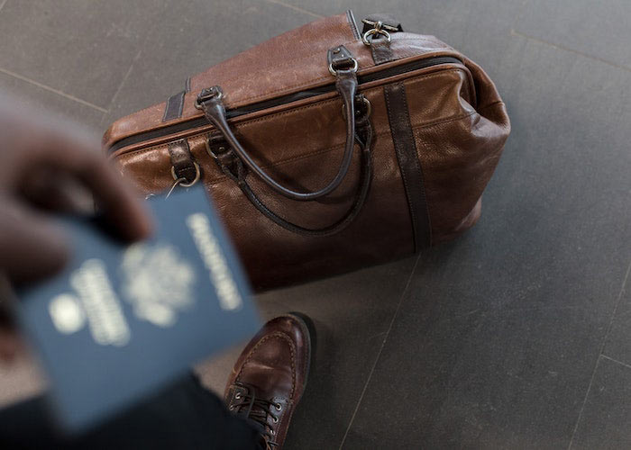 man holding passport id with leather luggage on the floor
