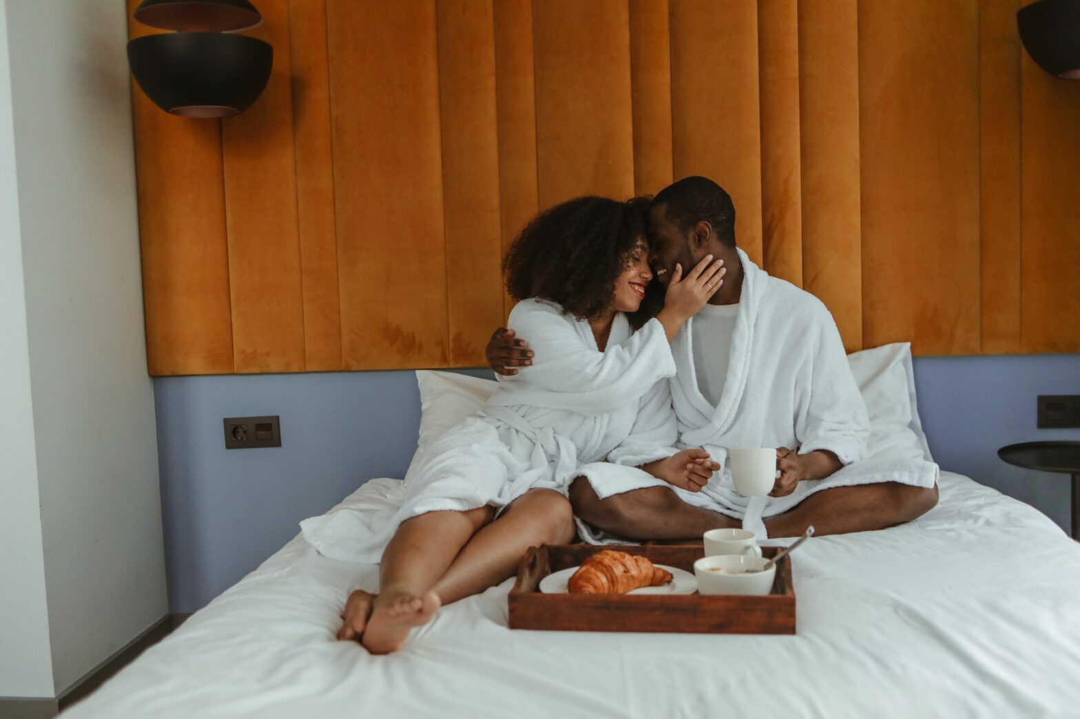 black couple in robes and room service in a hotel room