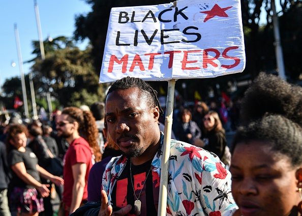 A man holding a placard that reads "Black Lives Matters" takes part in a demonstration of people, including employees of the country's social and reception centers and members of anti-racism associations, against the government's social politics, its recent decree restricting the right to asylum, and against racism on November 10, 2018 in downtown Rome.
