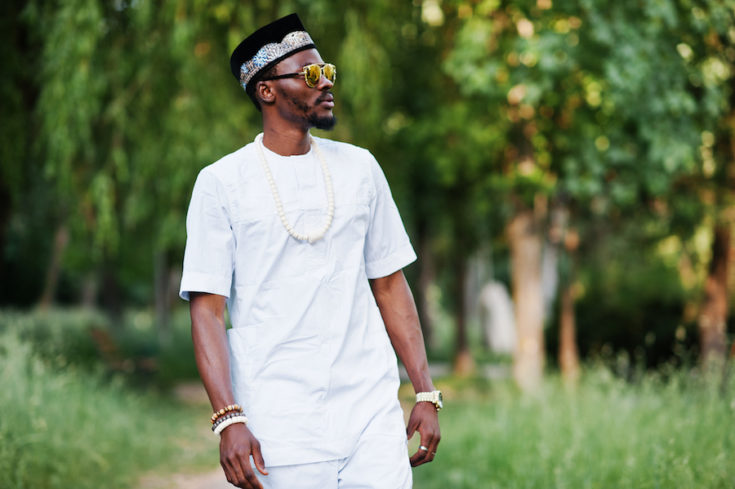 Portrait of stylish and rich black african american man on white clothes, sunglasses and hat