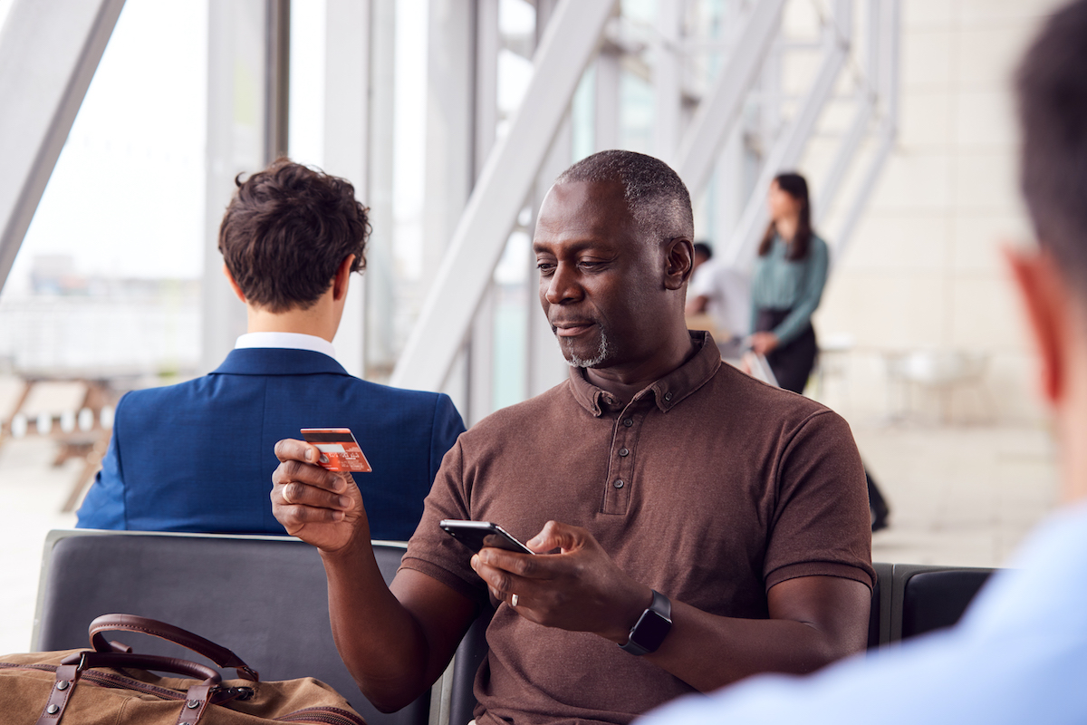 Black man sitting with credit card in hand in airport
