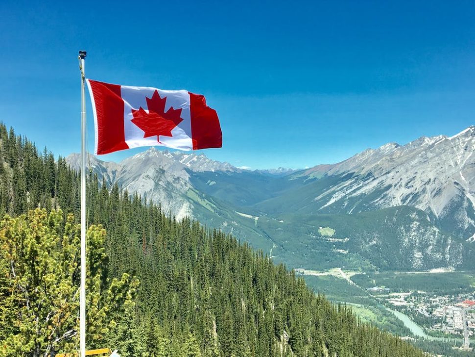 Canadian flag waving in the air with mountains in the distance