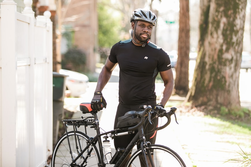 Black man wearing helmet while standing next to a bike outdoors