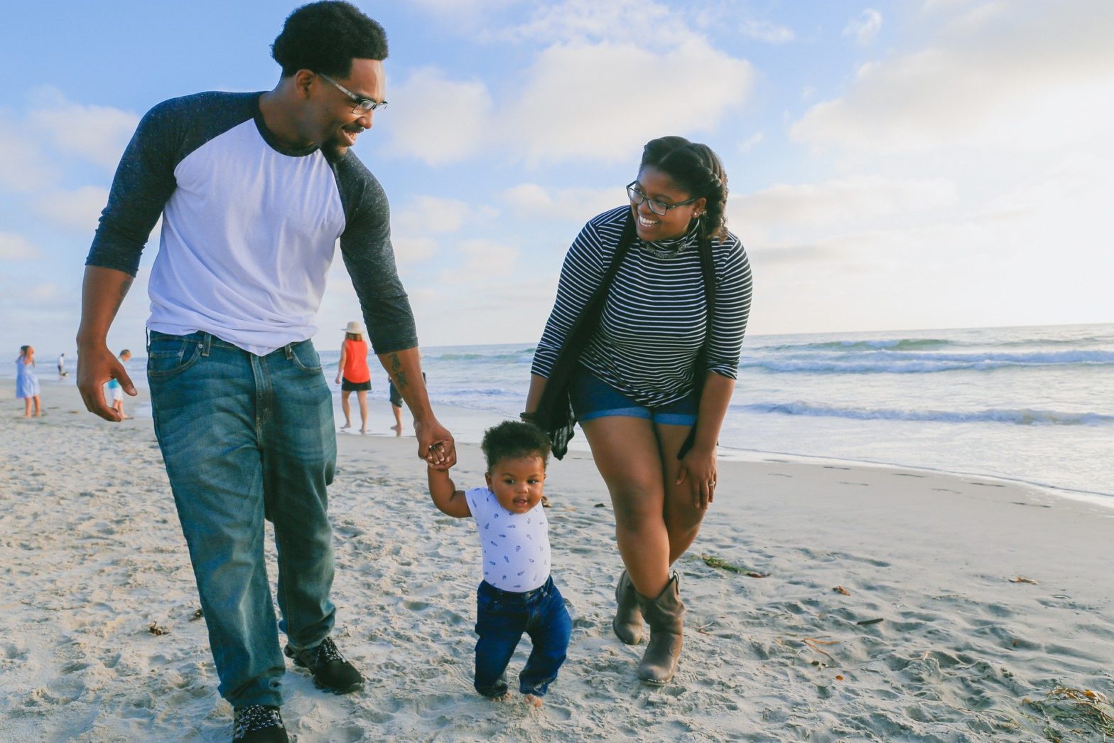 Black family with toddler walking along the beach - Unique vacation spots for families