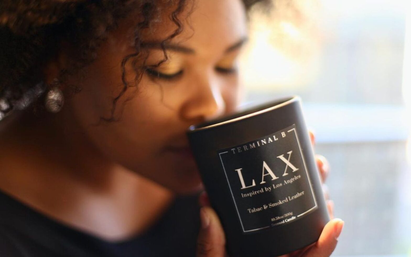 woman smelling airport code luxury candle by black-owned business Terminal B
