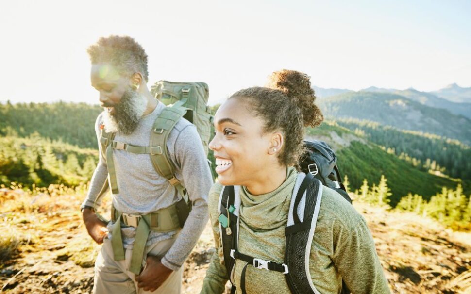 Black woman and man hiking with mountains in the distance