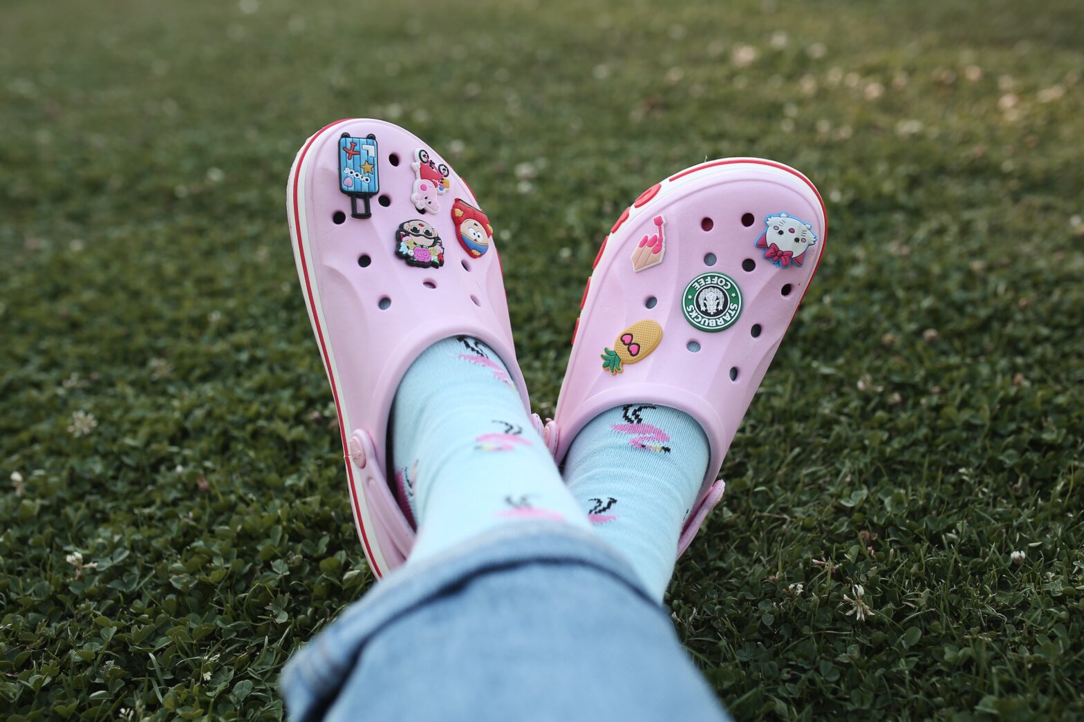 Pinks Crocs on woman's feet at the park in green grass - Best Crocs For Adventure