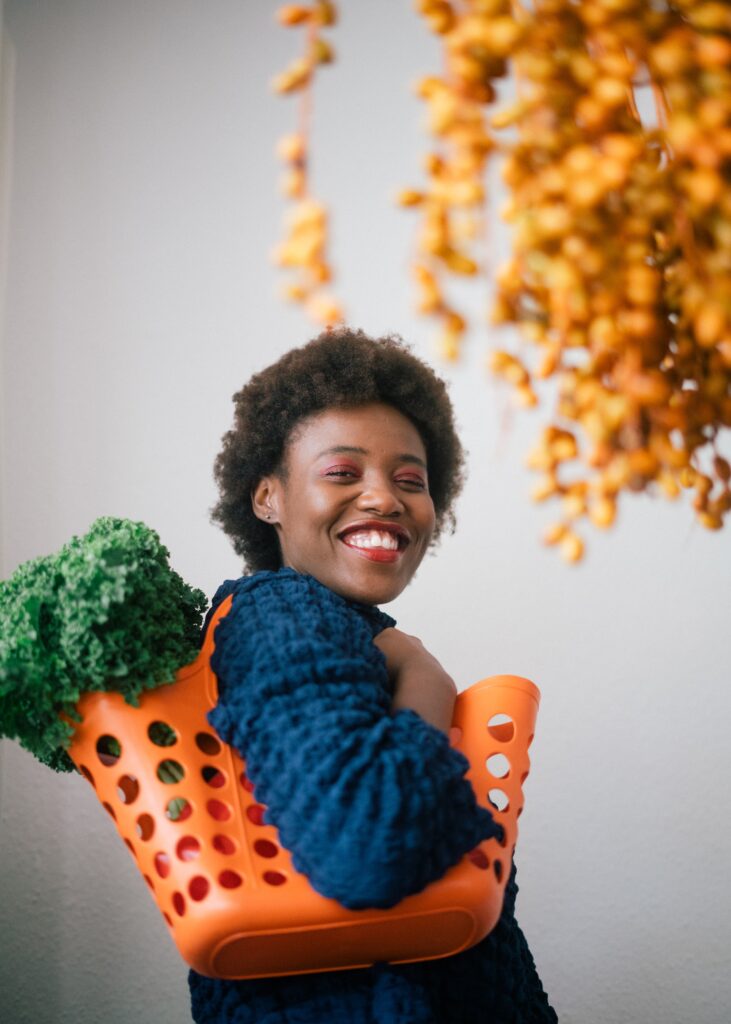 Black woman smiling while carrying a bag of vegetables - Earth Day Festivals