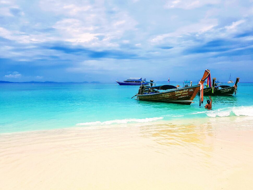 泰国普吉岛海滩海岸线上清澈碧蓝的海水中的传统木船