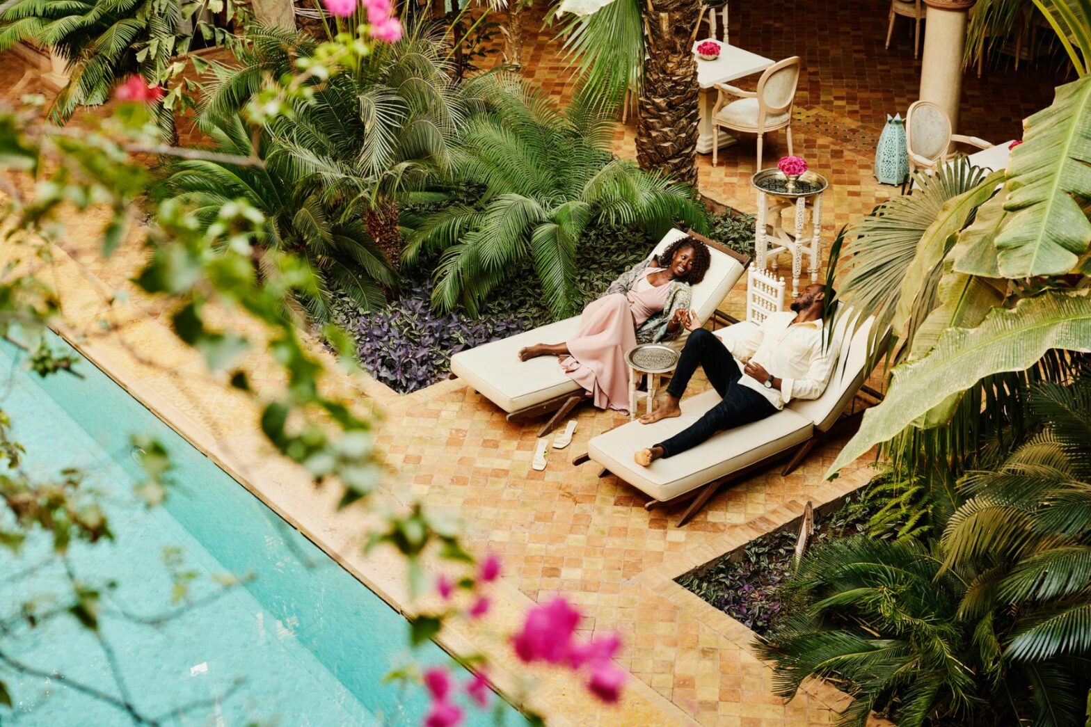 couple relaxing in lounge chairs by pool at luxury hotel