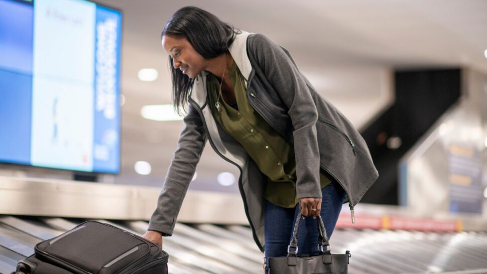 woman picking up luggage at airport baggage claim