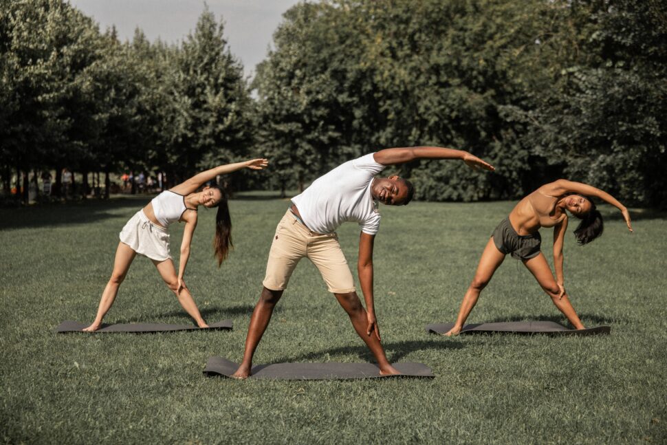 Black people doing yoga outdoors on a grass lawn