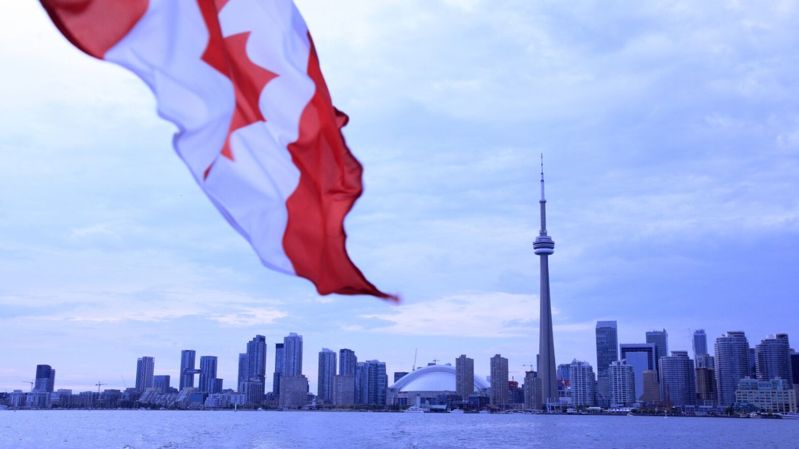 Canada flag waving with Toronto skyline in the distance