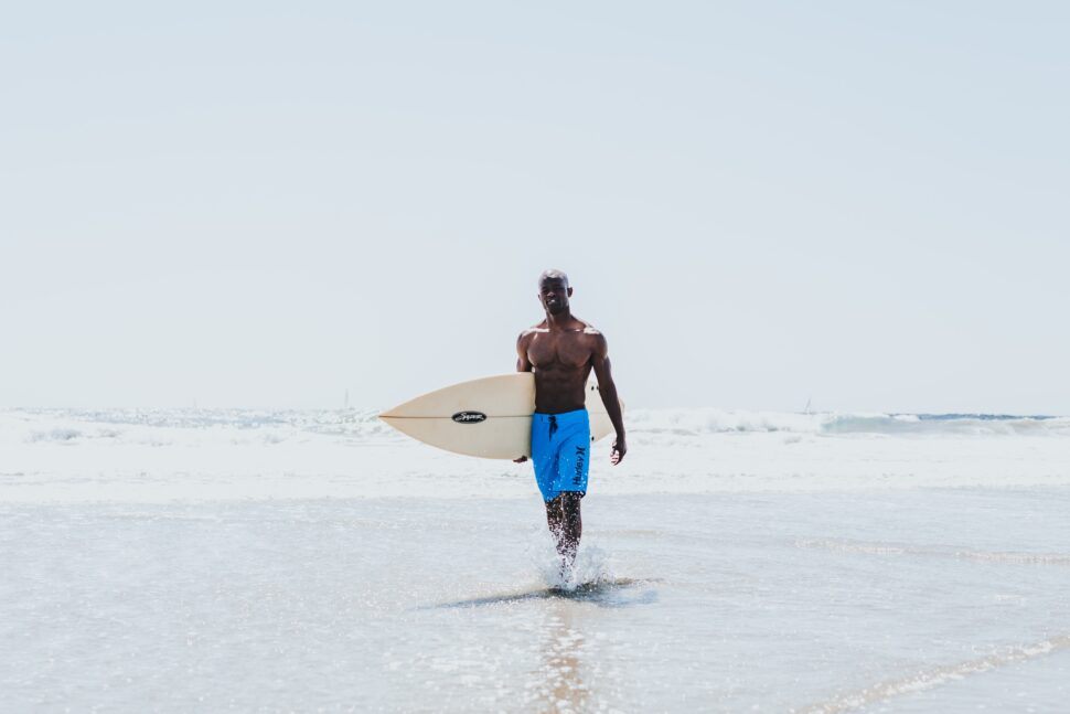 black man with surfboard on a beach