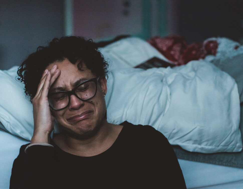 woman crying beside bed