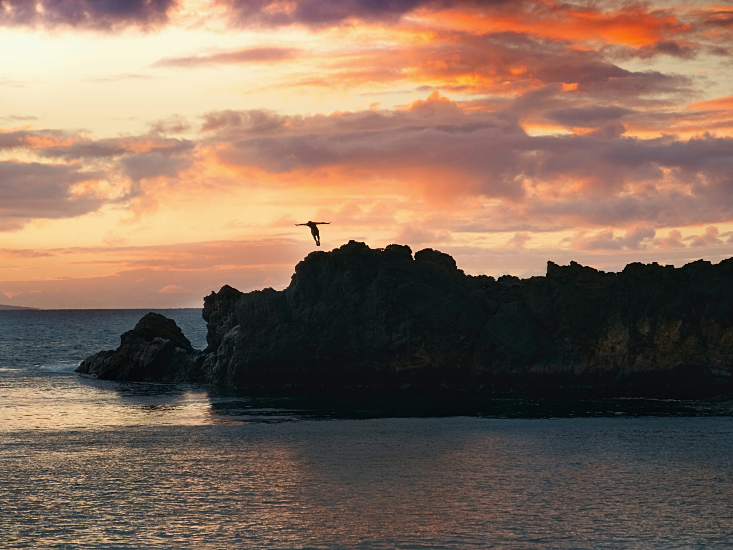 China Walls is unique and slightly dangerous site in Hawaii. Learn more about its origins. 
pictured: A cliff jumper enjoying the Hawaiian sunset and getting into the water