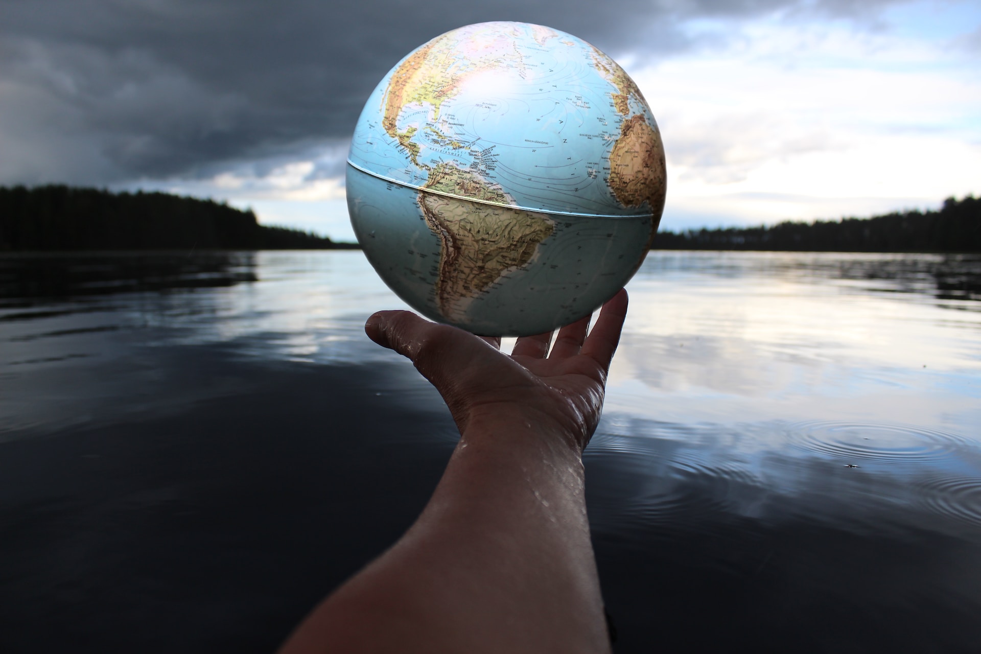 A hand holding a globe above water