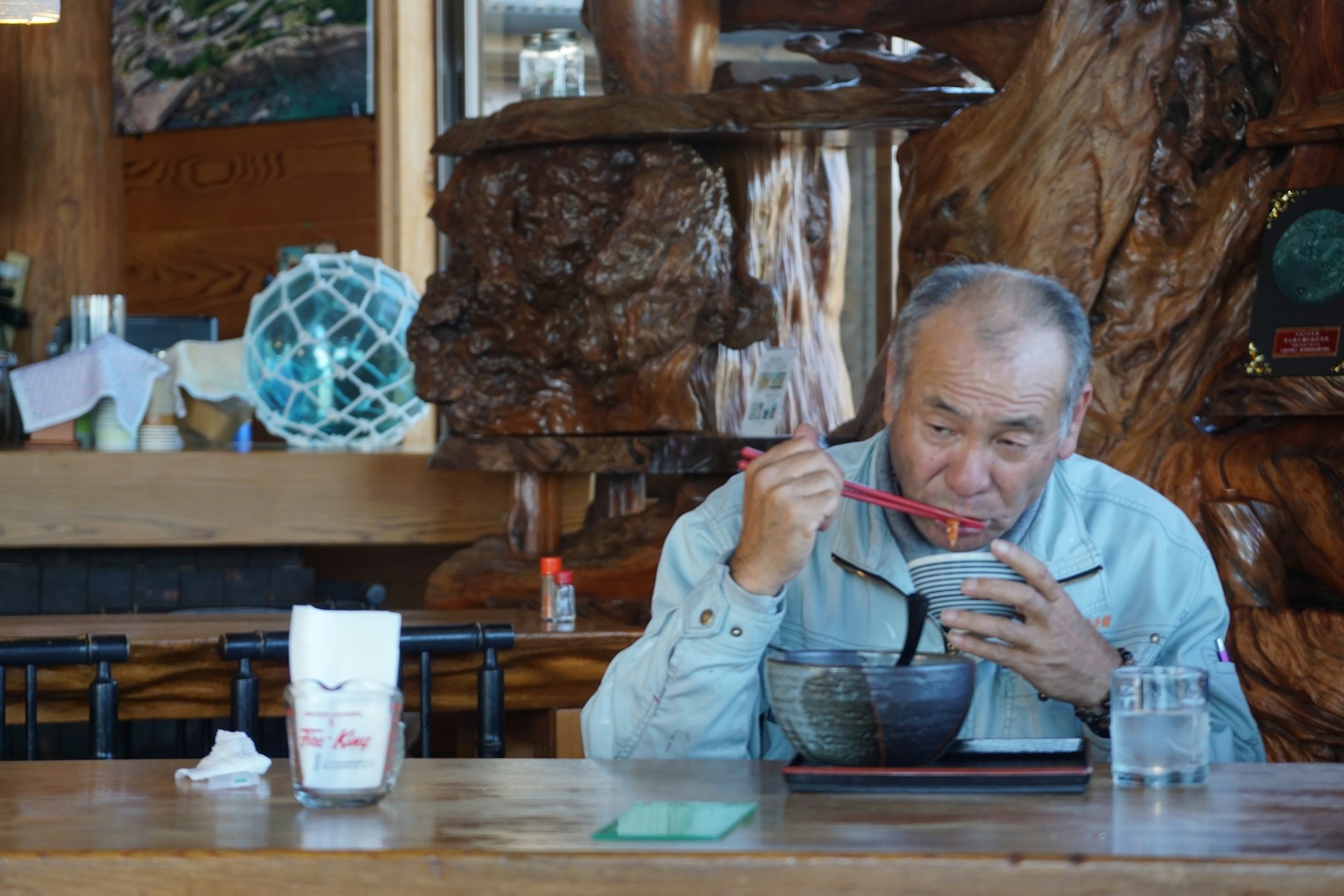 A Japanese man sitting at a table alone and eating.