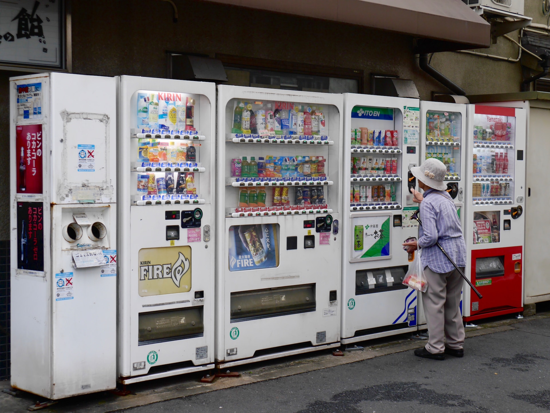A woman standing in front of five vending machines in Japan.