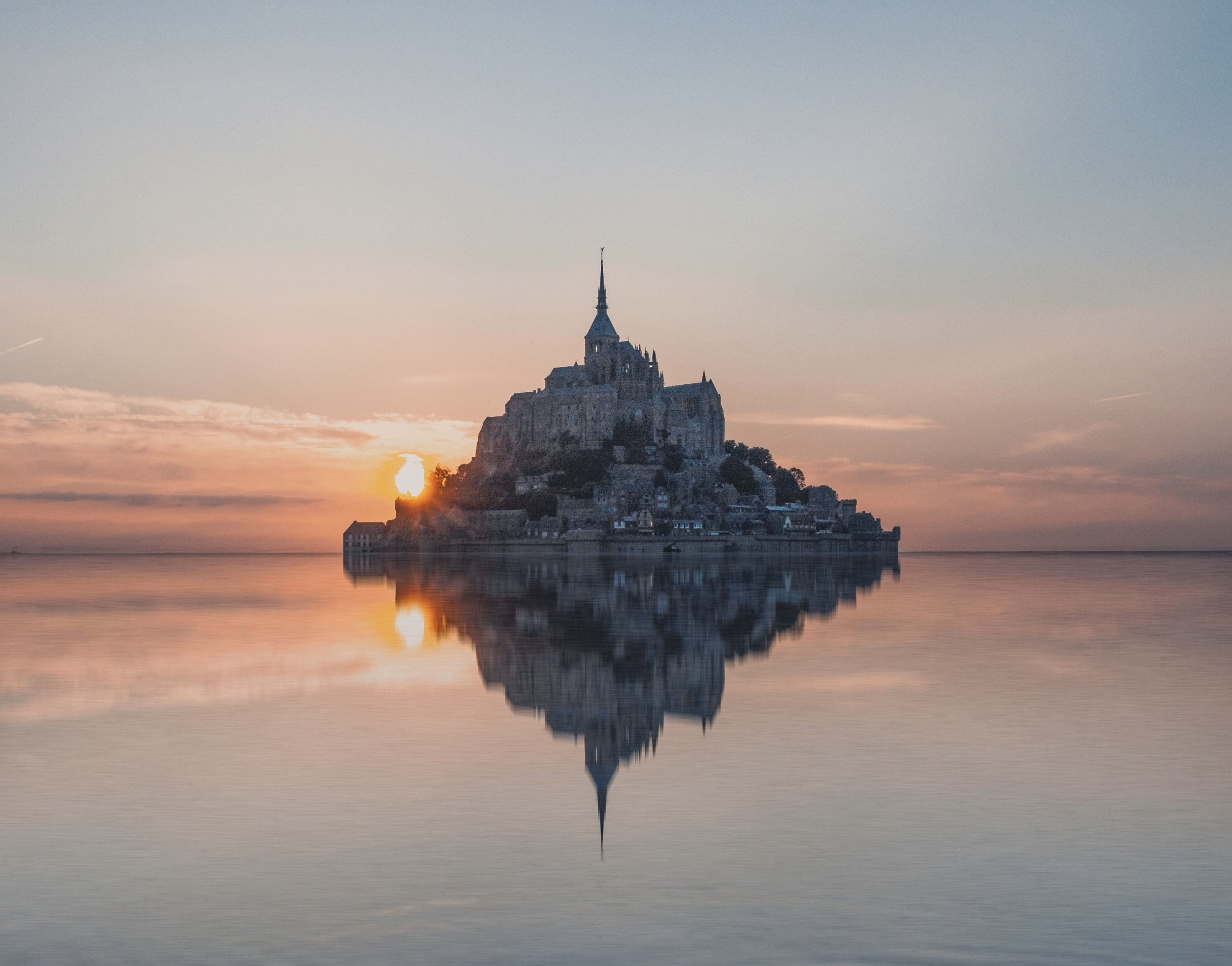 The tides of Mont-Saint-Michel vary and can alter the experiences of tourists.
Pictured: Mont-Saint-Michel at high tide during sunset 