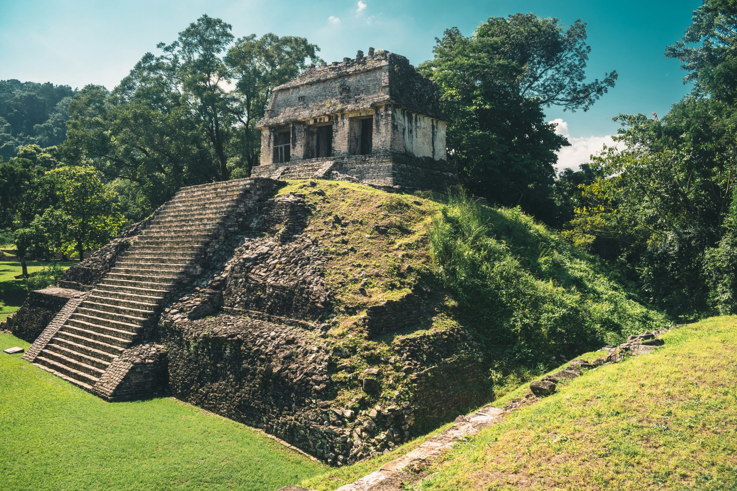 The Palenque site is an ancient location which takes an extensive commute. 
pictured: Palenque ruins with green grass growth up the pyramids hill 