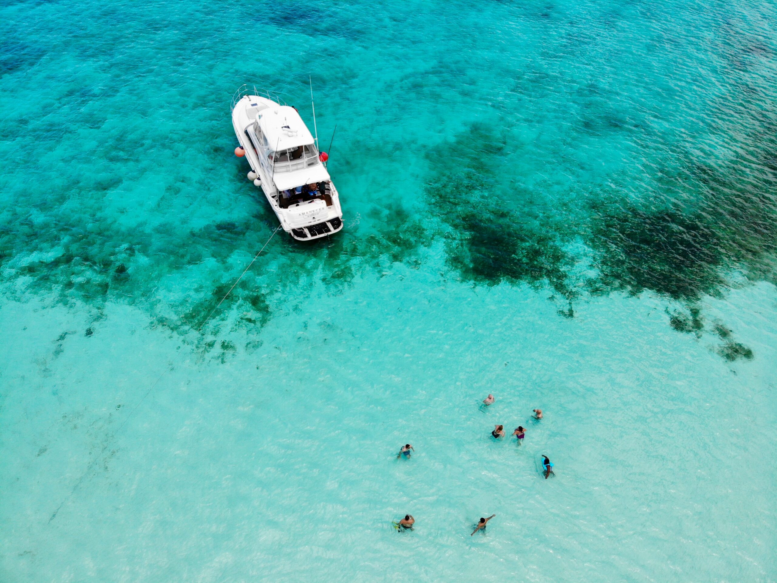 Learn more about the safety of tourists in Cozumel, Mexico. 
pictured: Cozumel, Mexico's beach with tourists enjoying the turquoise waters near a boat 