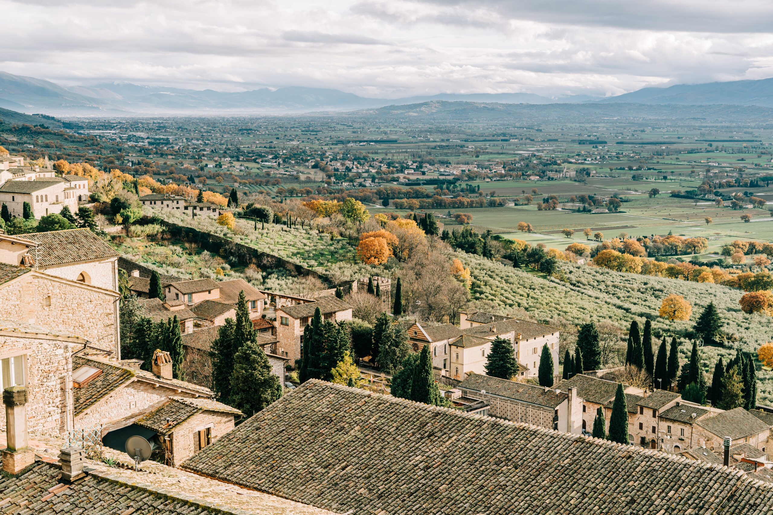 Umbria is a historic region of Italy's countryside. 
pictured: An overlooking view of a village of Umbria, Italy with expansive green land  