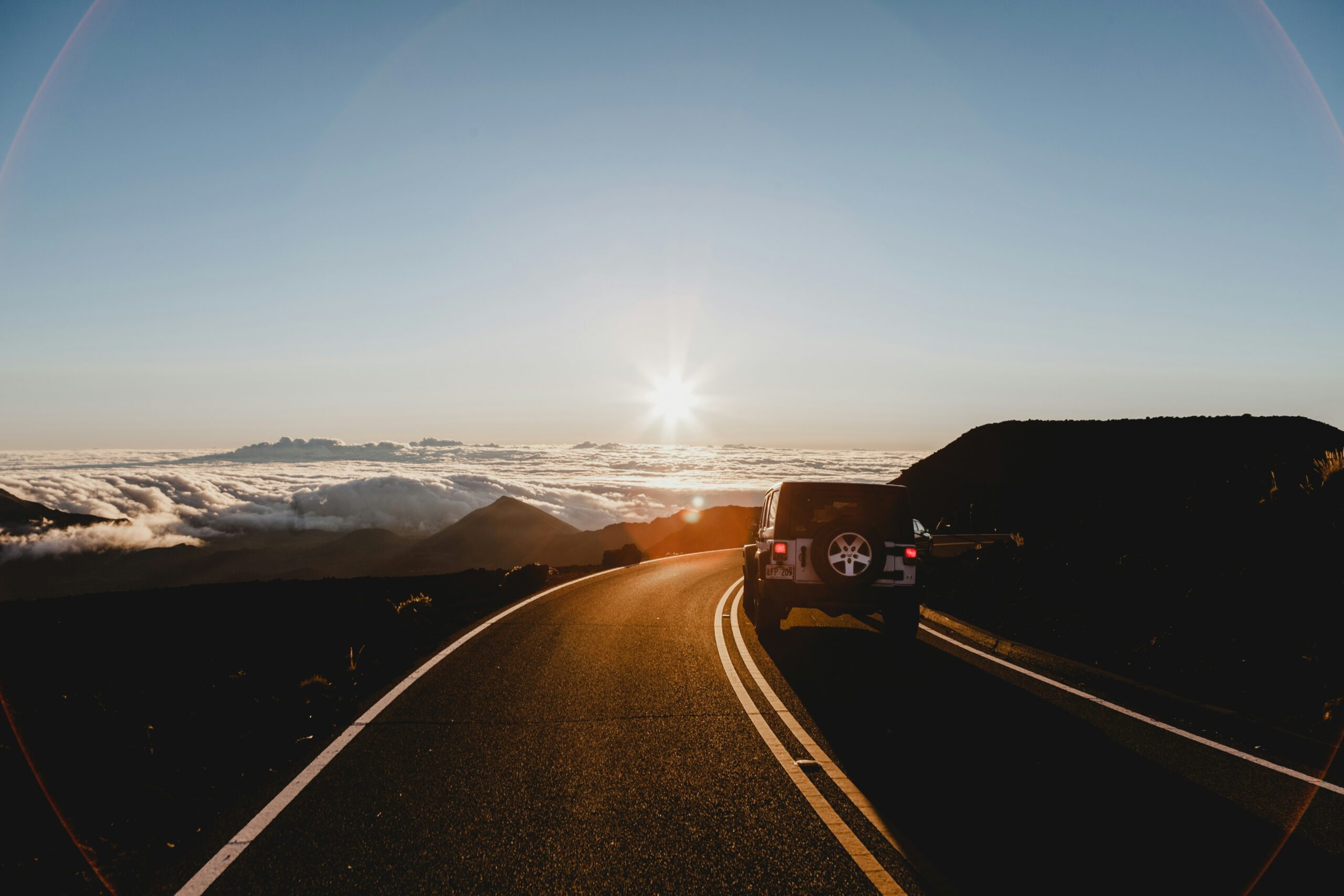 These modern games provide great entertainment for long road trips. 
pictured: A jeep rolling by a stunning view of the clouds and sun, on a tall hill 