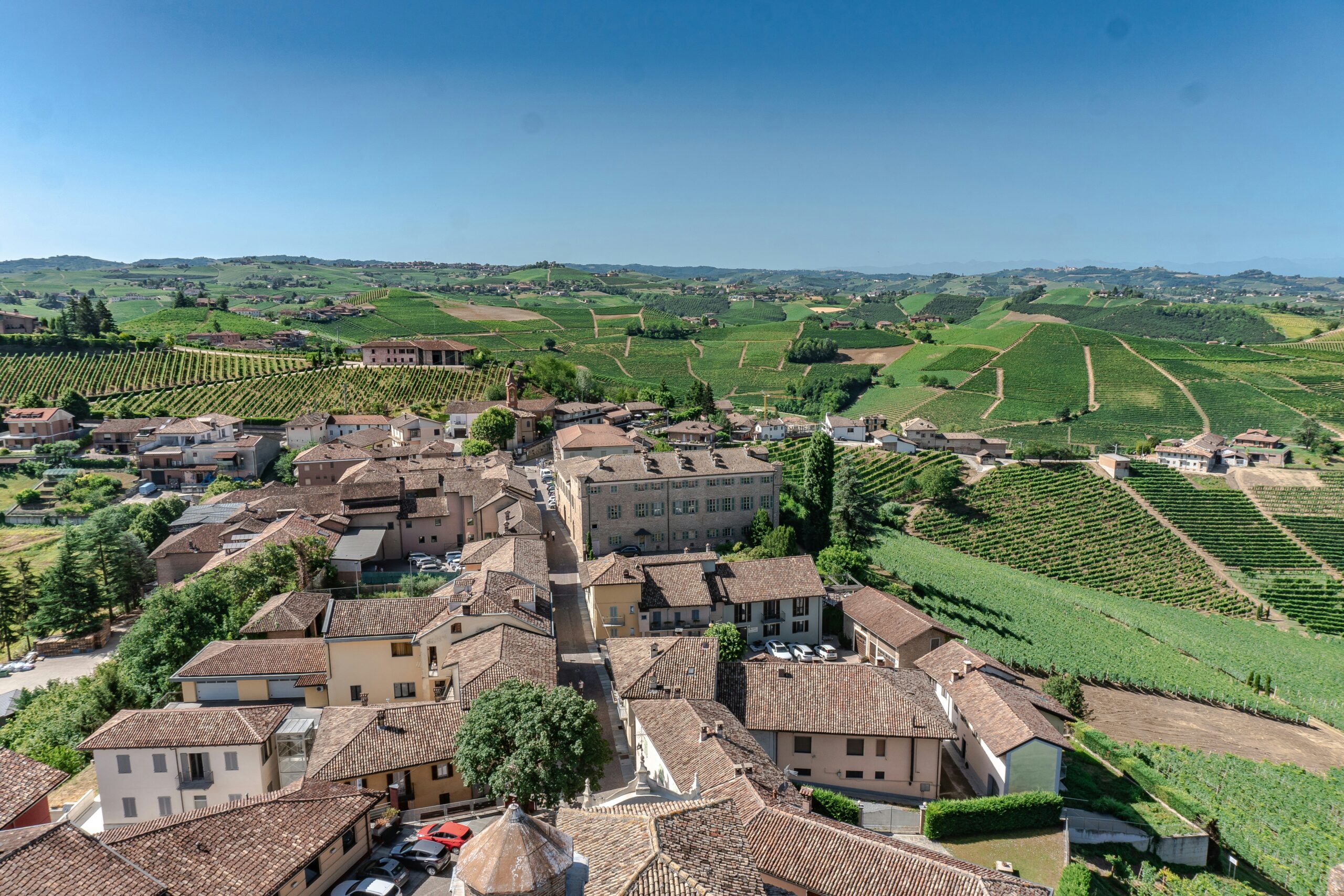 Learn more about Piedmont, the popular region of Italy that offers great lake views. 
pictured: the grassy areas of Piedmont, Italy with a populated village at the center