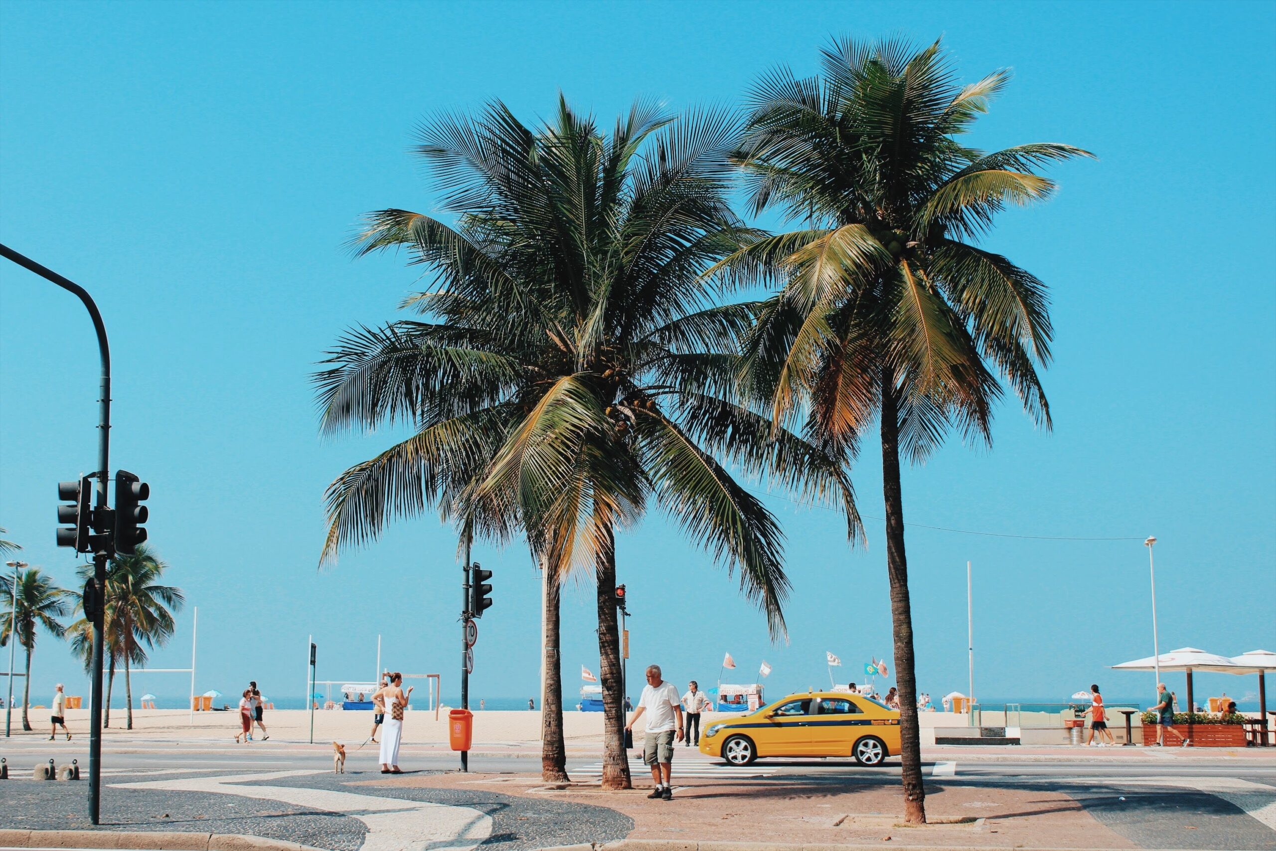 Since Rio de Janeiro is a generally safe place to visit and is tropical, the best times to visit vary. Check out the benefits of each season. 
pictured: Rio de Janeiro's streets on a clear sunny day embellished with palm trees and pedestrians walking around 