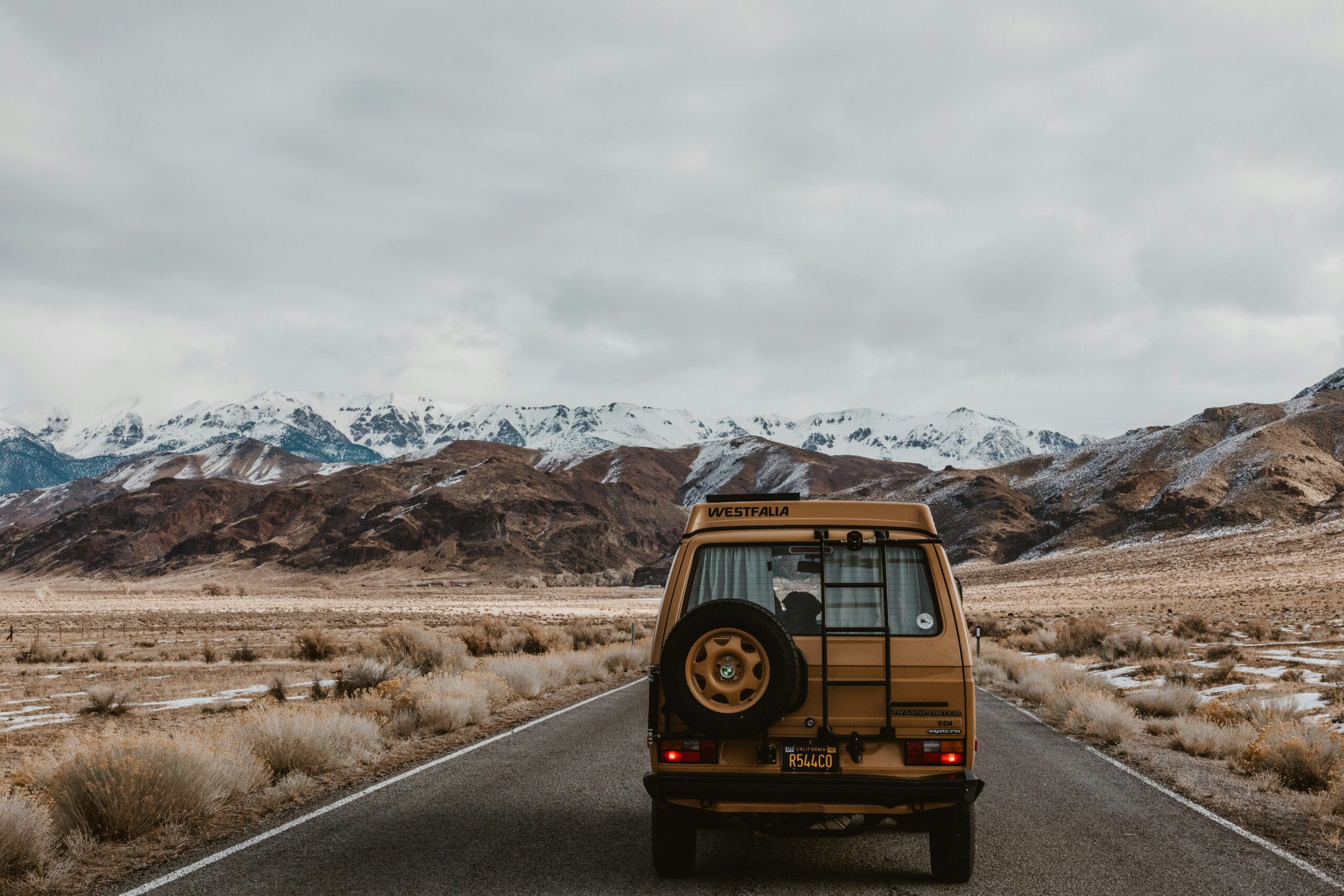 These traditional games are great ways to pass the time on extended road trips. 
pictured: A family sized van driving along a one-way road near snowy mountains 