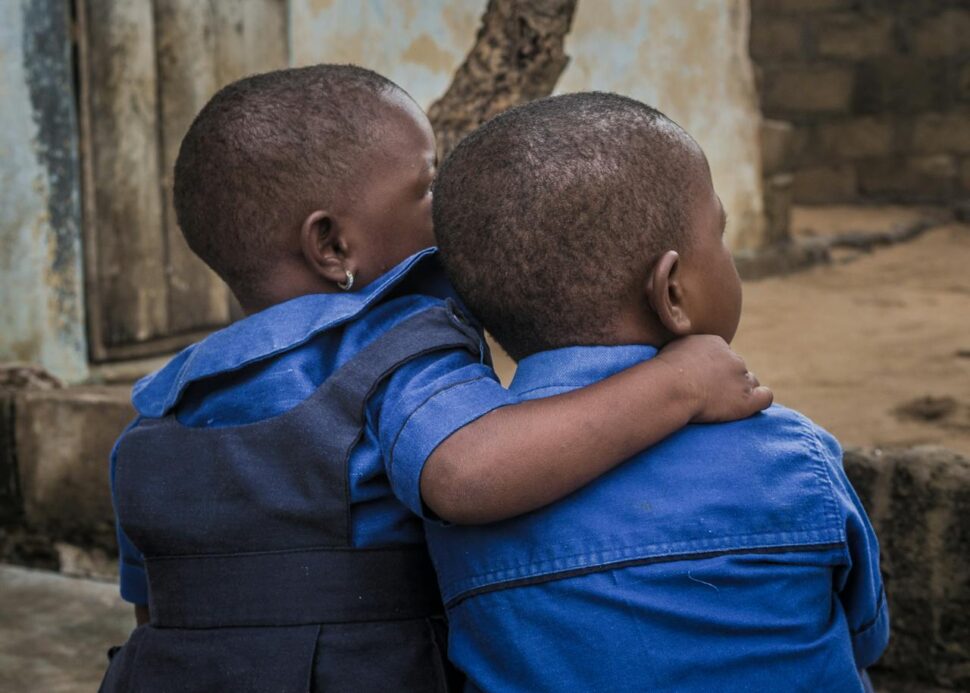 The backs of two kids embracing each other