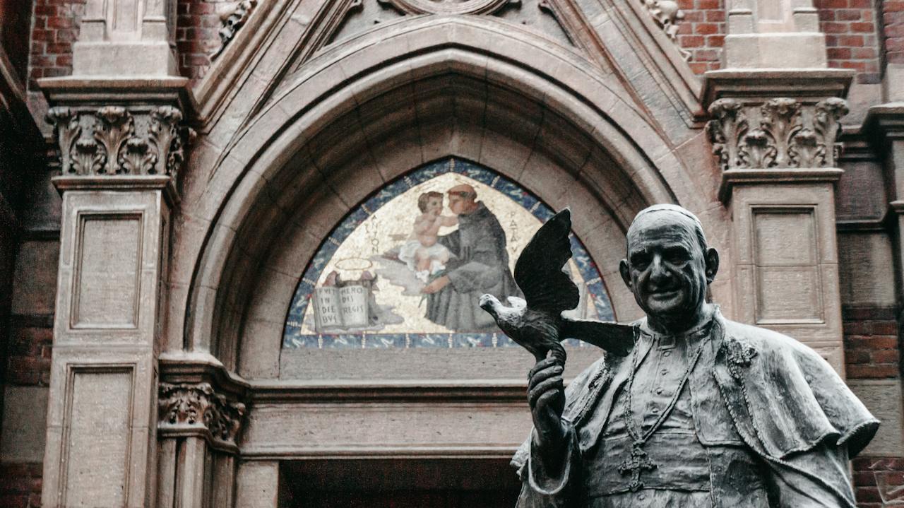 a statue of Pope Francis outside of a cathedral 