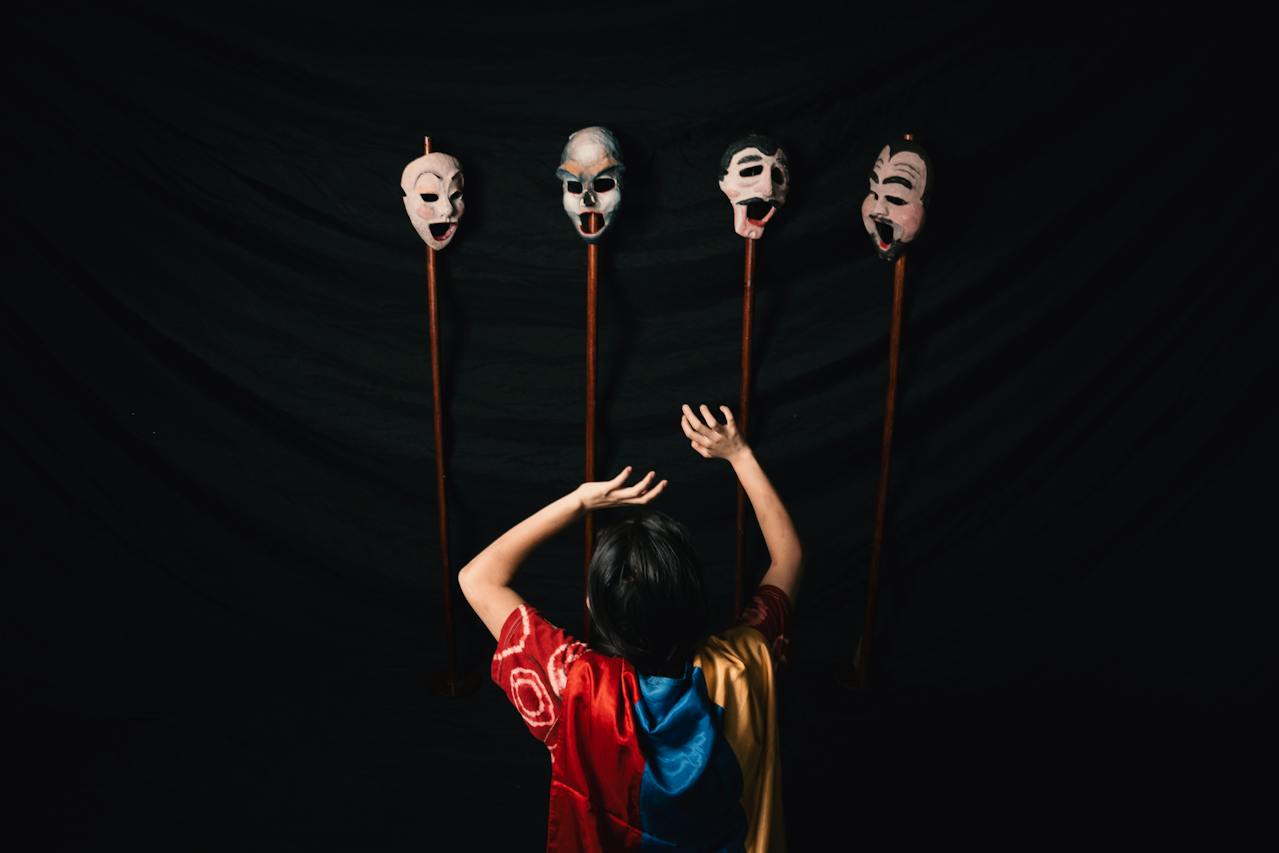 A person in a black background looking at four masks