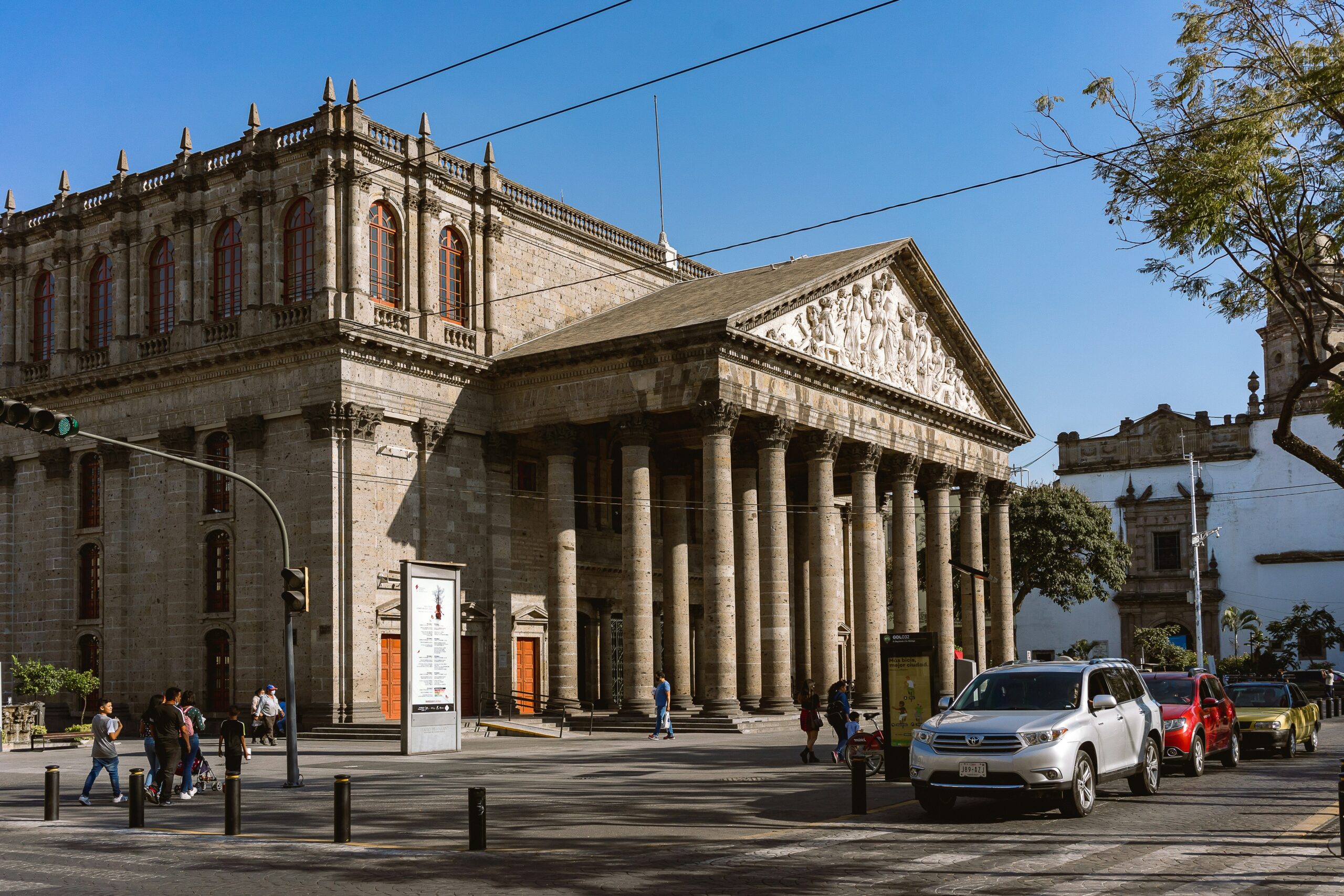 Guadalajara has public transportation that is accessible and makes exploring the city easier and safer. 
pictured: a historic building in Guadalajara with many pedestrians exploring the area on foot 