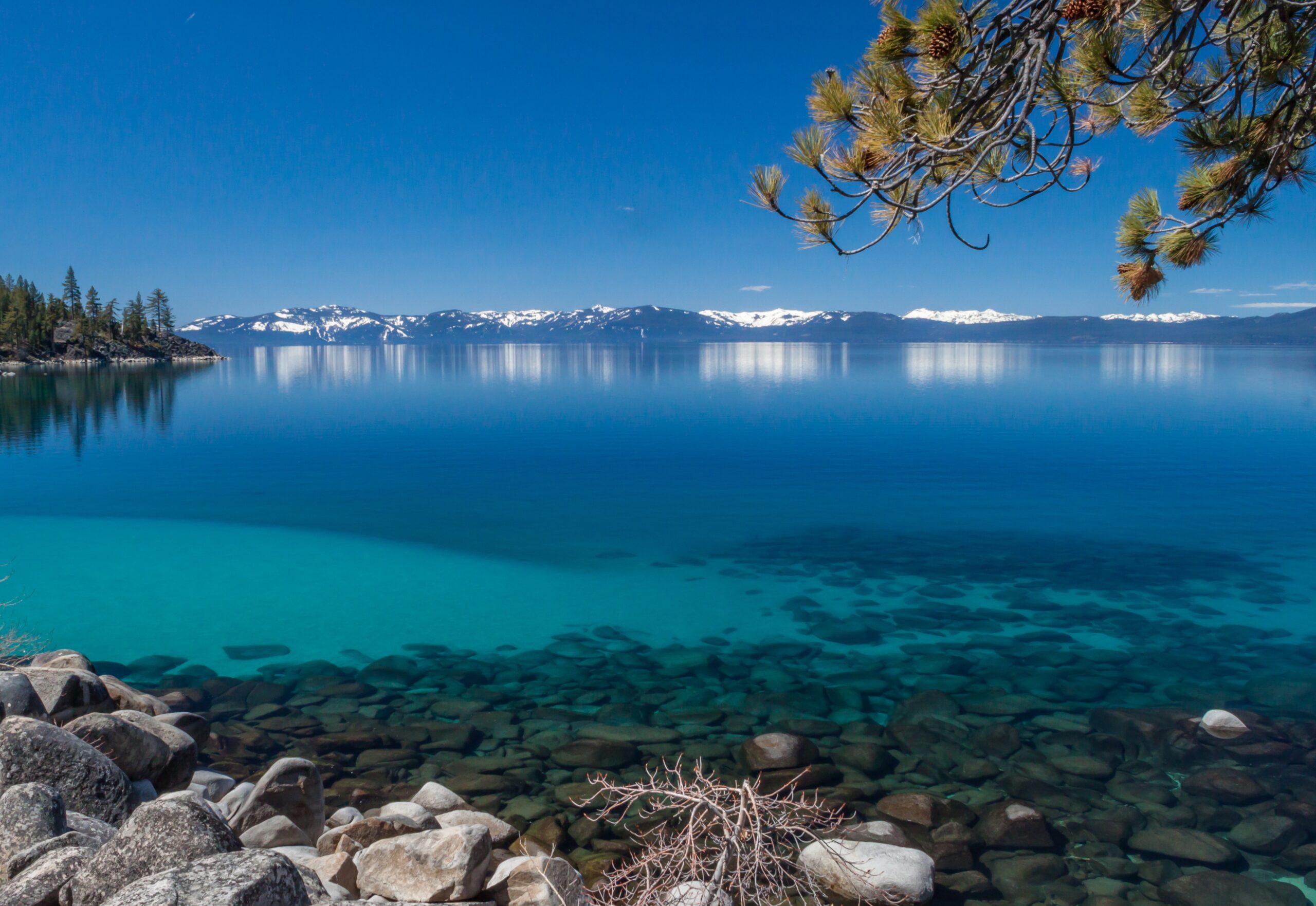 Lake Tahoe is a popular destination and filming location of the newest Top Gun film.
pictured: The turquoise waters of Lake Tahoe with snowy mountains in the distance 