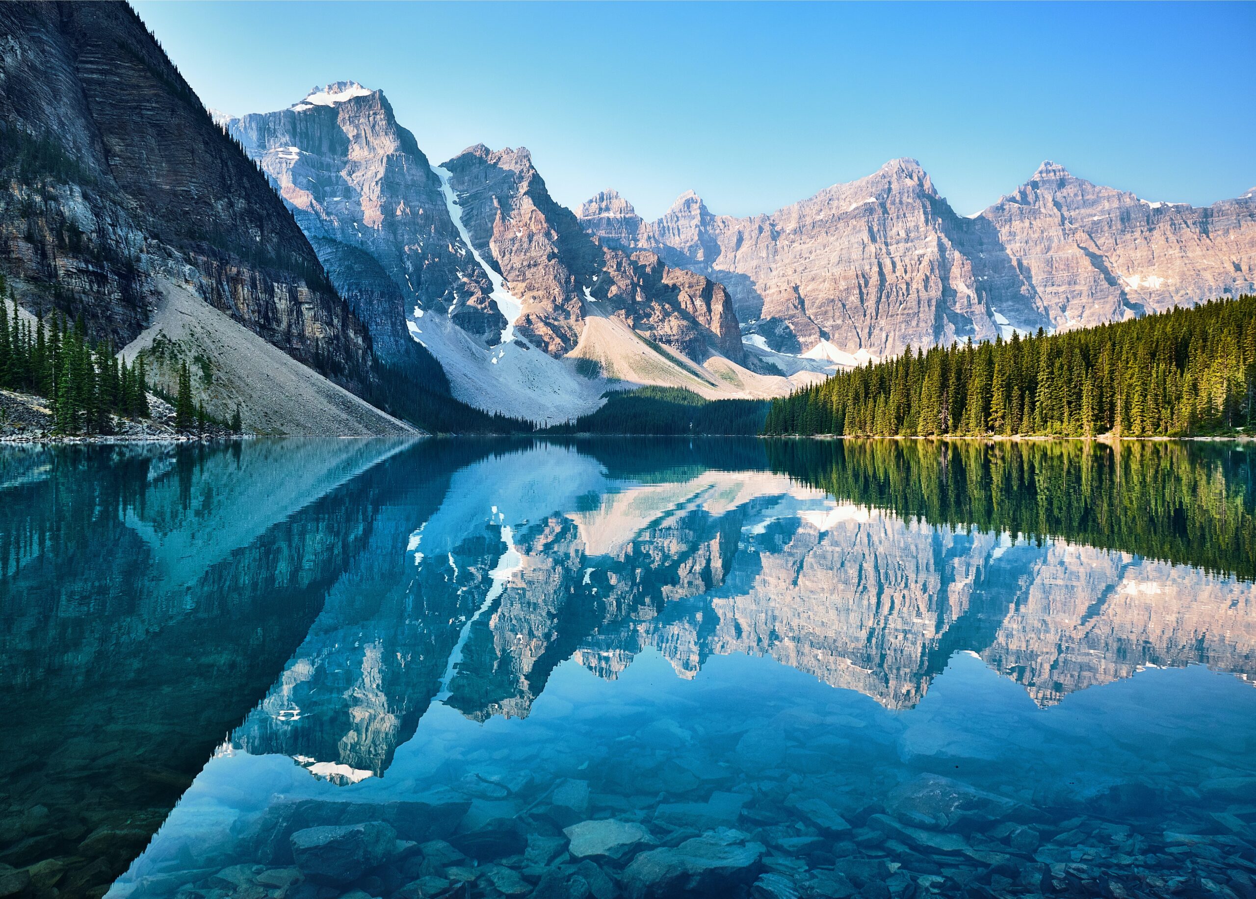 Canada is a stunning and nearly perfect destination for winter vacations. 
Pictured: the snowy mountains, lush green trees and rivers of Canada 