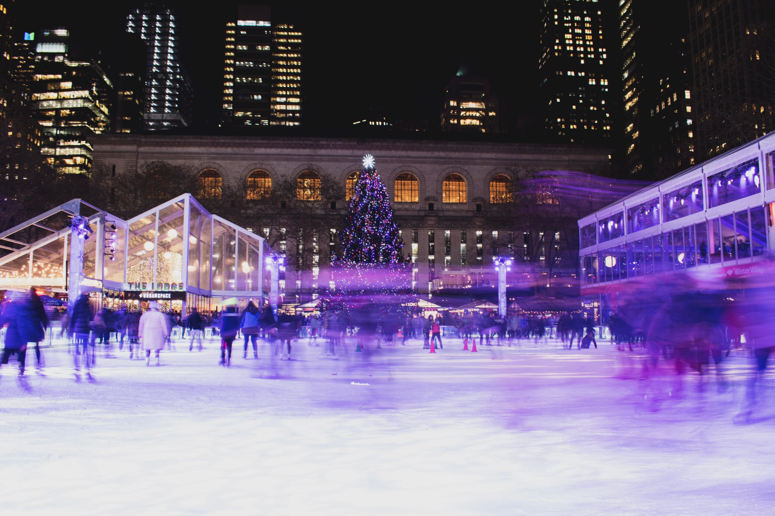 These are the most festive activities to do in NYC during Christmas time. 
Pictured: a skating rink with passing skaters and twinkling Christmas lights 