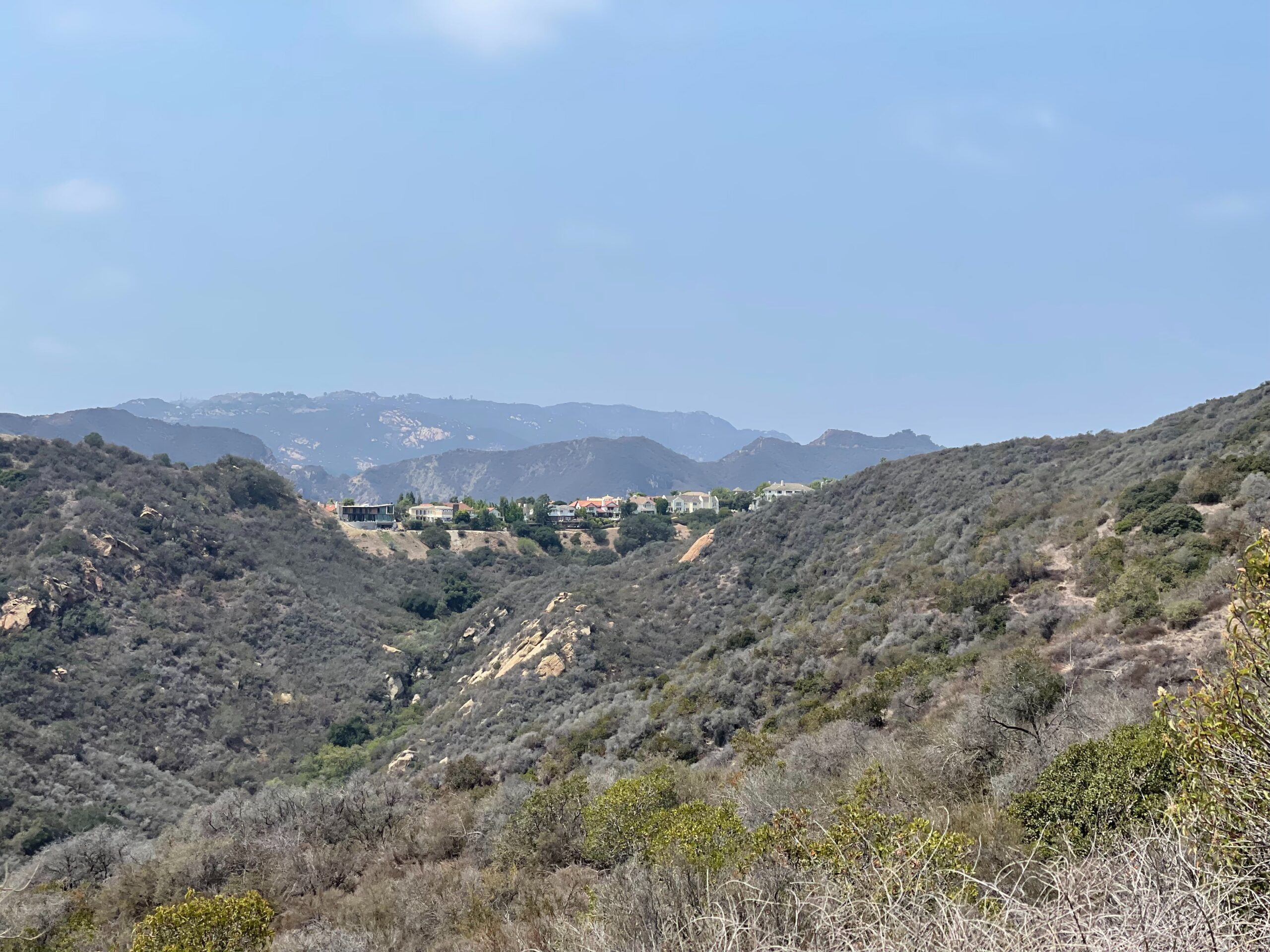 The Santa Monica Mountains are a stunning site in California that were a major filming location for the television series “MASH”.
Pictured: the Santa Monica Mountains and green shrubbery with a town in the distance 