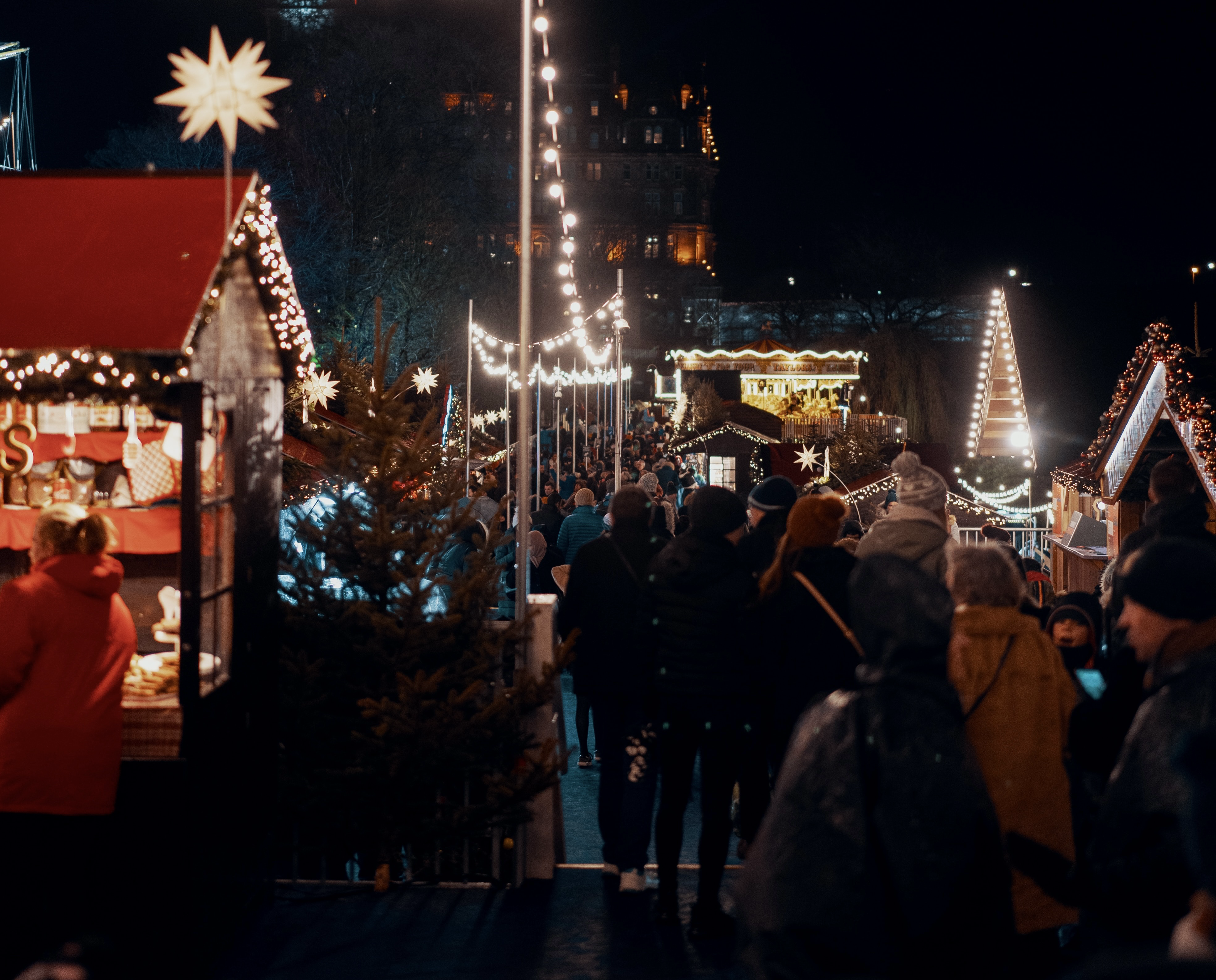 Scotland has Christmas markets that visitors will not want to miss. 
Pictured: a Christmas market in Scotland at night with festive lights and a large crowd 
