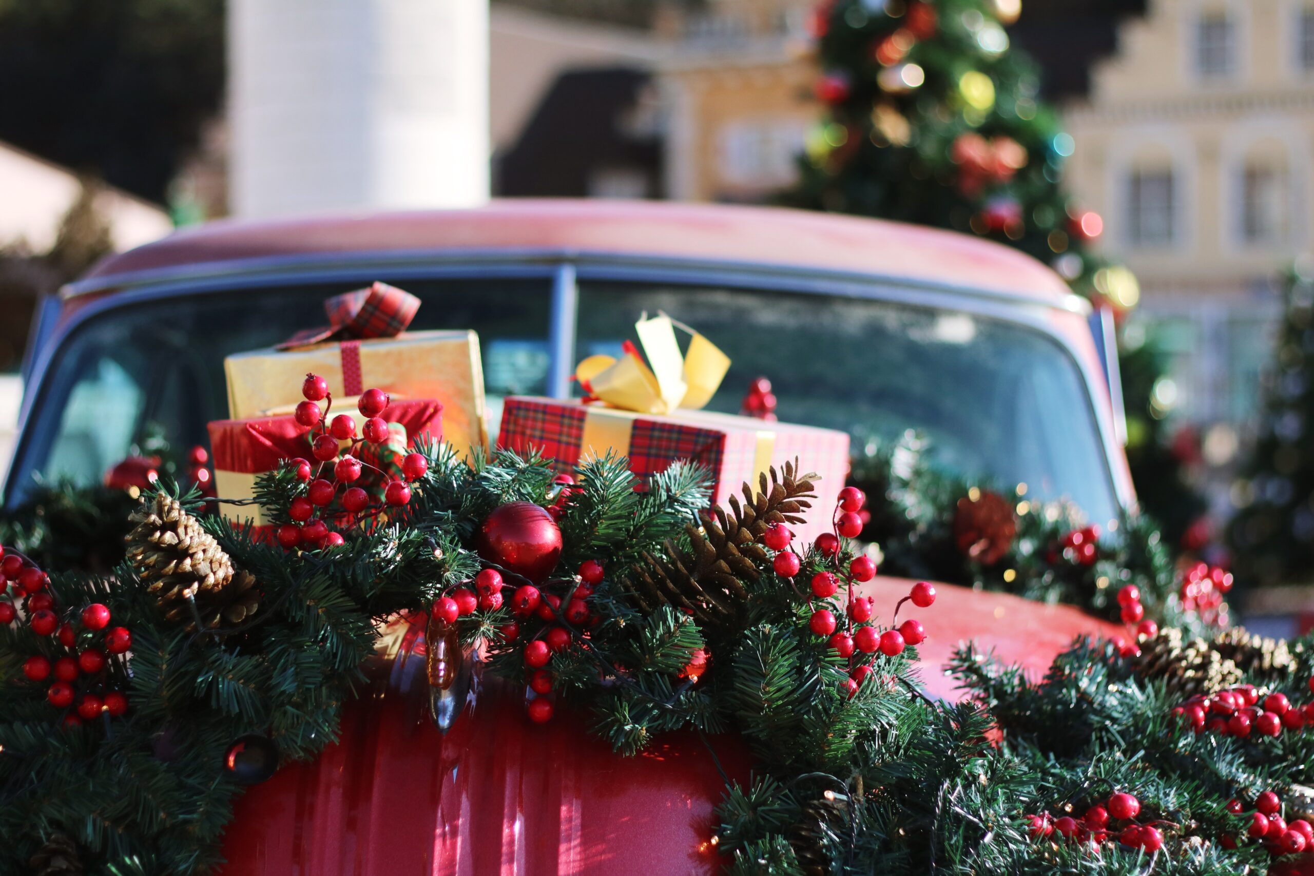North Carolina is a popular state to visit for Christmas. 
pictured: a red car in North Carolina streets covered in pine and Christmas presents with a decorated tree in the background 