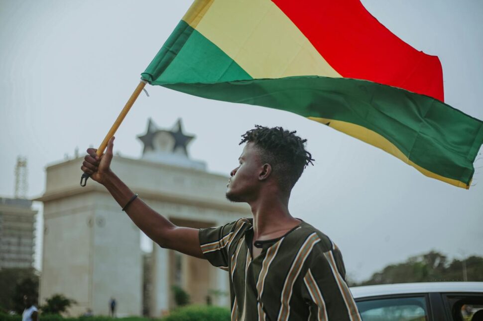man holding flag of Ghana near Black Star Square - Destinations to visit in your 20s