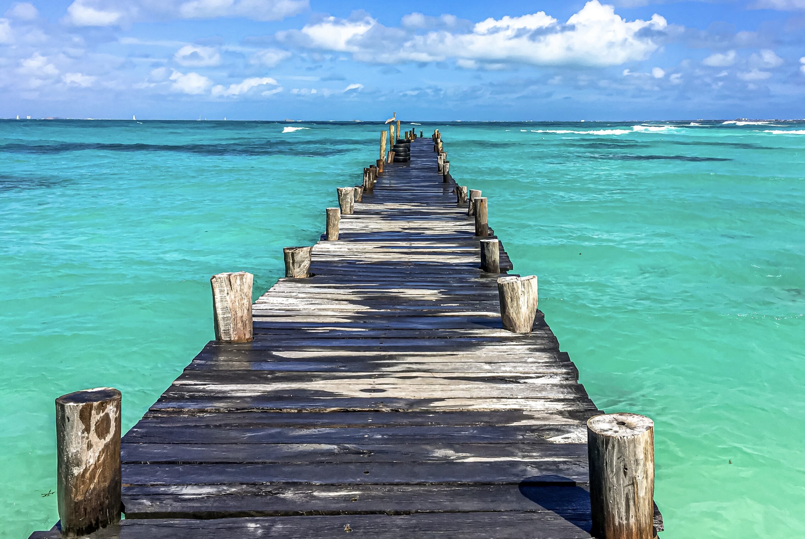 Cancun is a safe travel destination that is not difficult to navigate. 
pictured: a pier of Cancun with clear waters and a cloudy sky 
