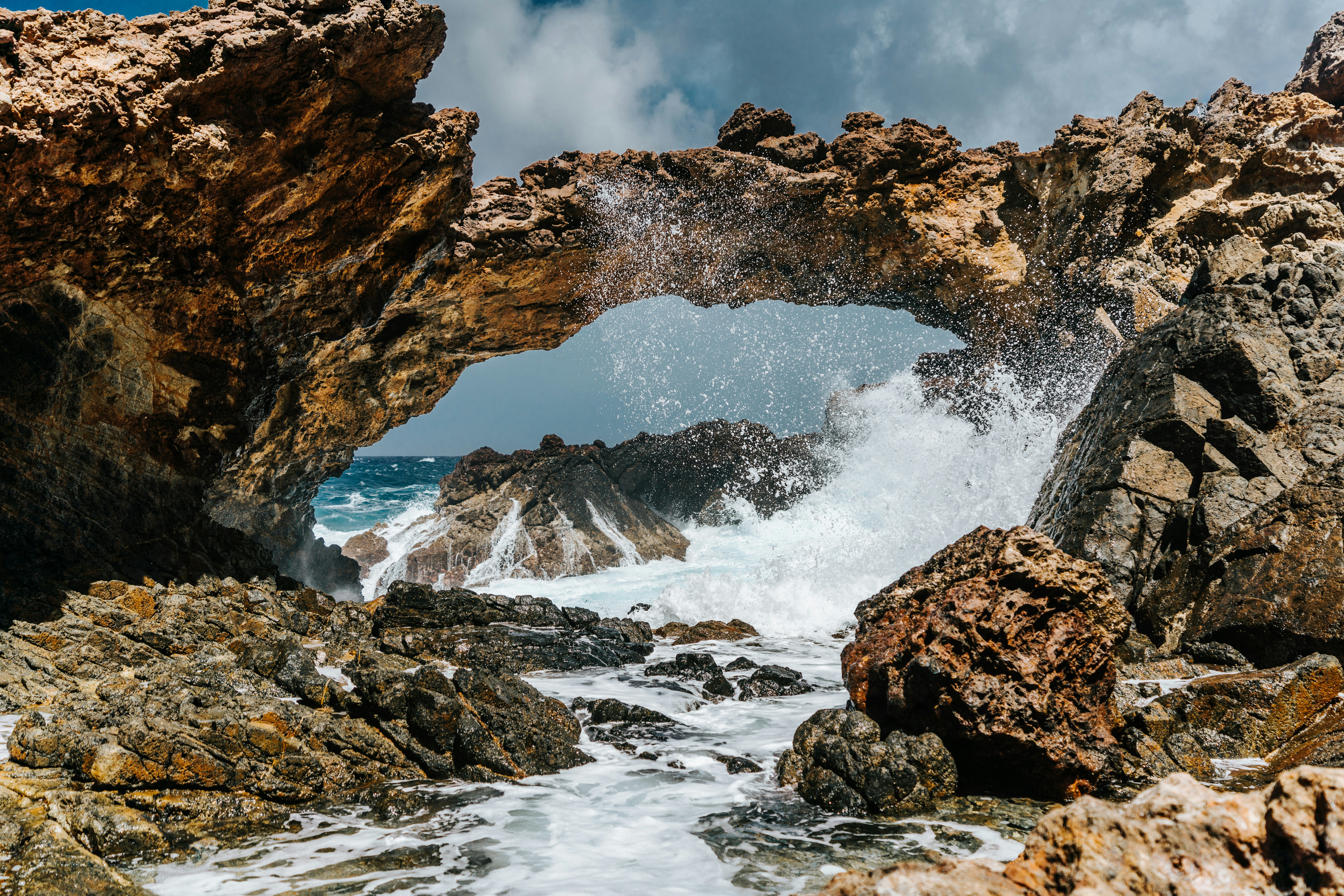Check out these official travel advisories with the best information on Aruba's safety level. 
pictured: the rock formations and crashing waves of Aruba's ocean 