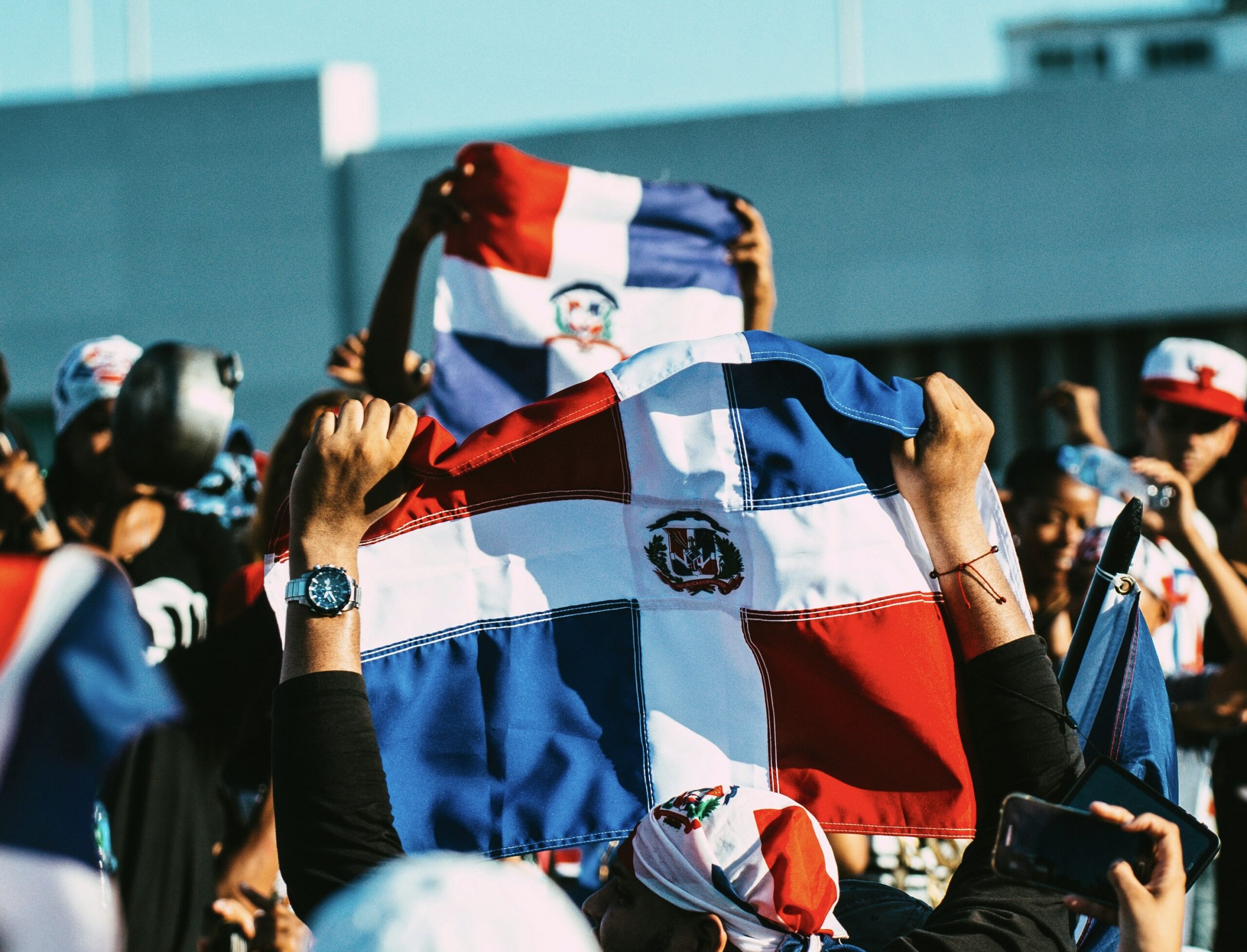 The Dominican Republic is a relatively safe place that travelers should fell welcome in. 
pictured: a gathering of citizens holding Dominican Republic flags up 