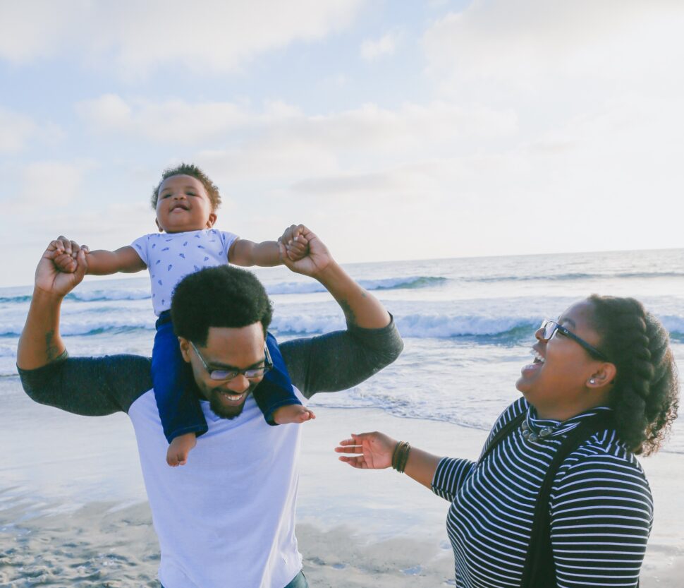 black family on the beach laughing with baby