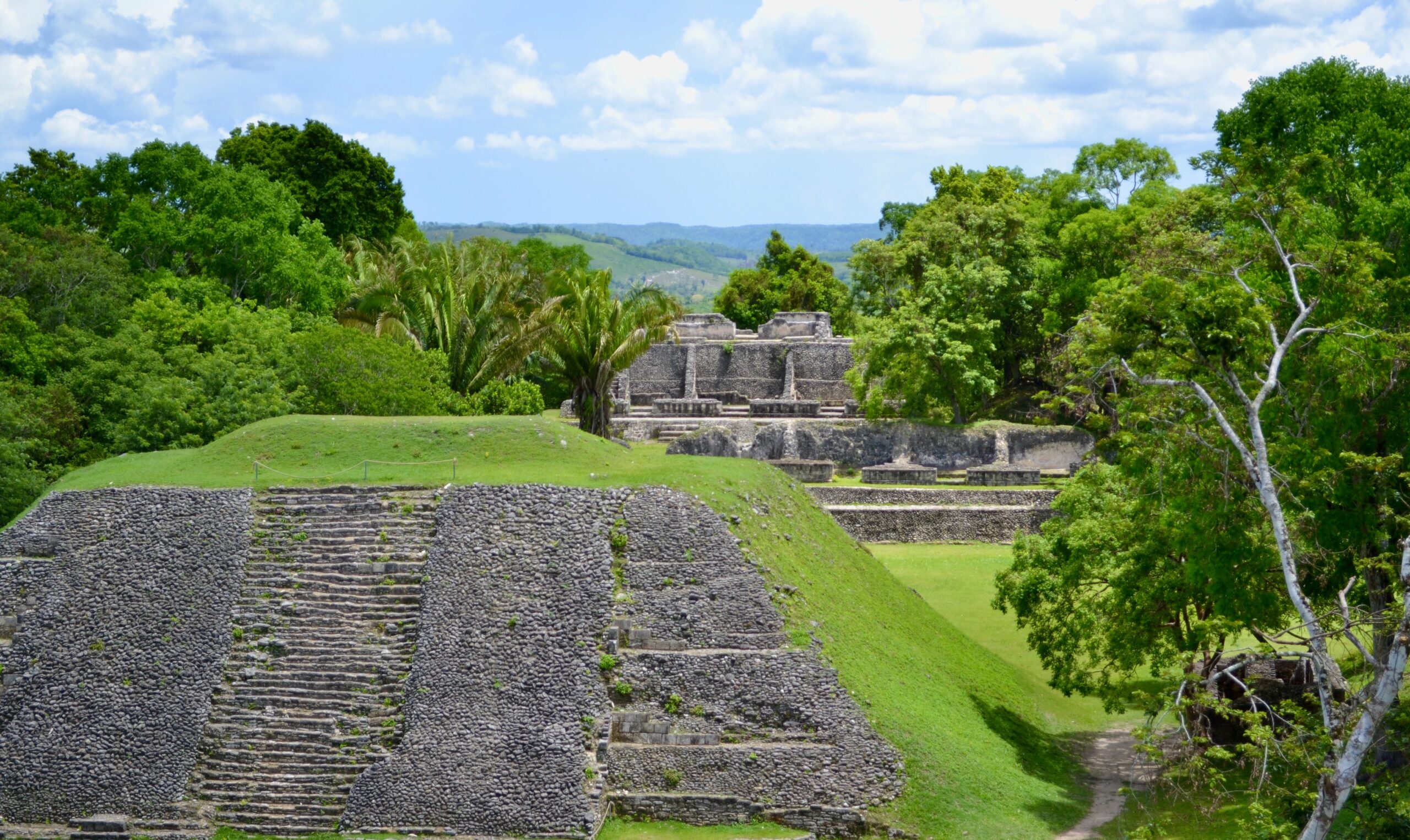 Belize is generally considered to be safe but there are ways travelers can make their trip even safer. 
pictured: the lush green hills of Belize and Mayan structures on a bright blue day