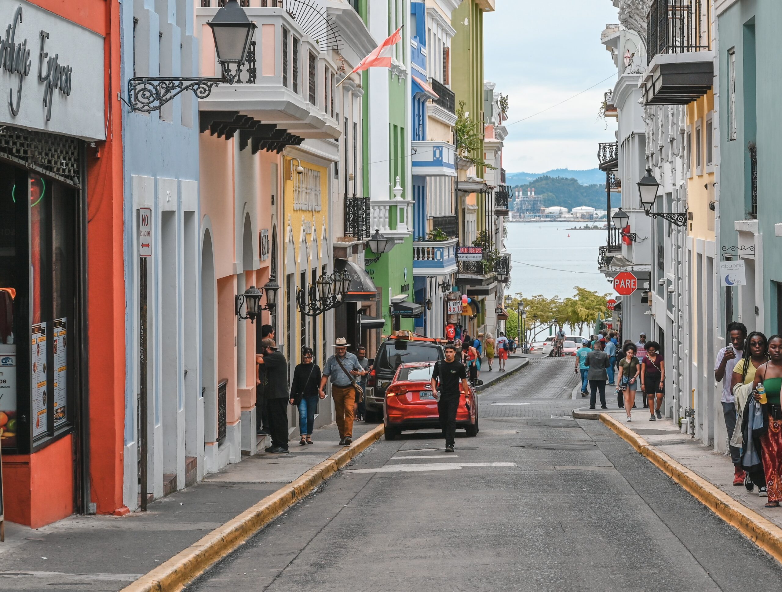 Tourists can rest assured that Puerto Rico is considered pretty safe, Learn more about the few crime concerns for visitors to consider. 
pictured: a bustling street of Puerto Rico with pedestrians and cars passing by 