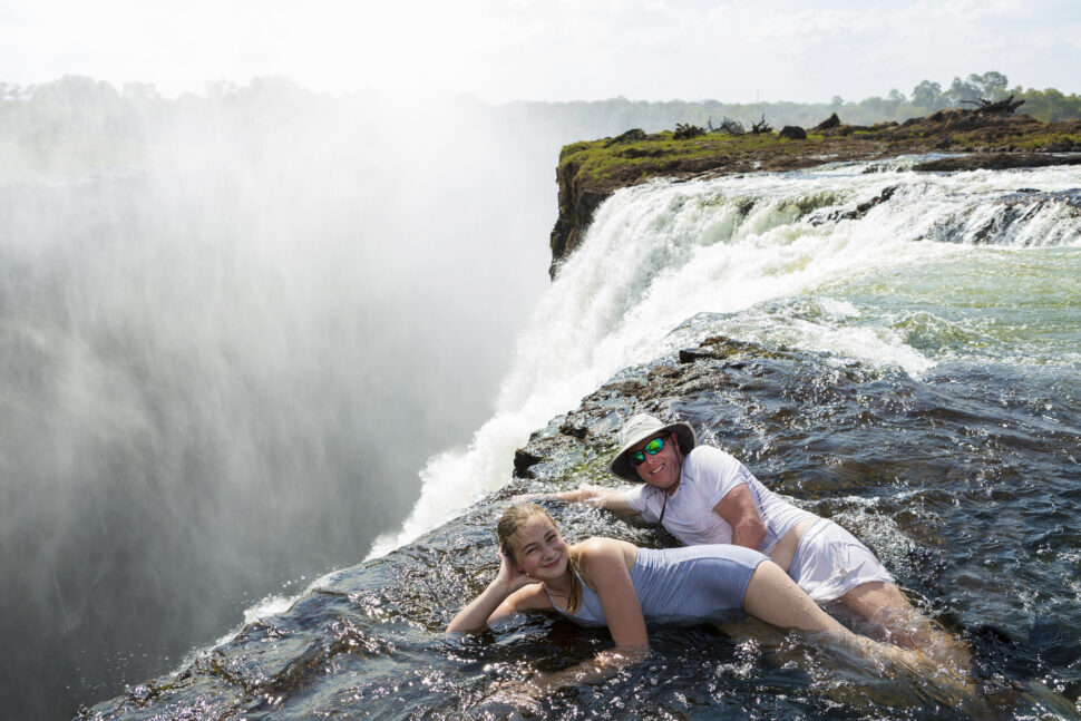 Man and girl on edge of Devil's Pool