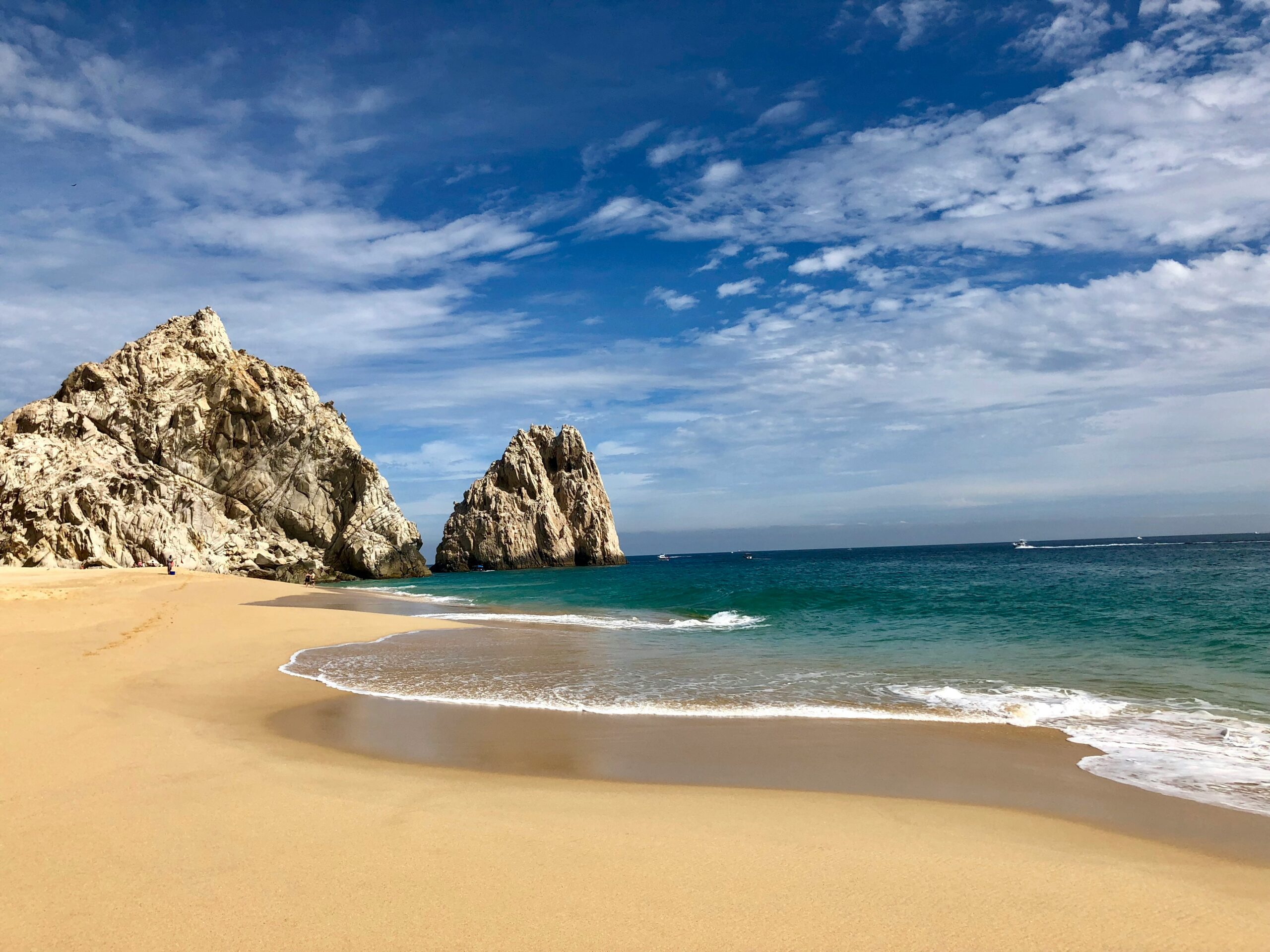 Travelers should check out these intimate beaches in Mexico. 
Pictured: a Mexican beach with cliffs and turquoise waters on a bright cloudy day 